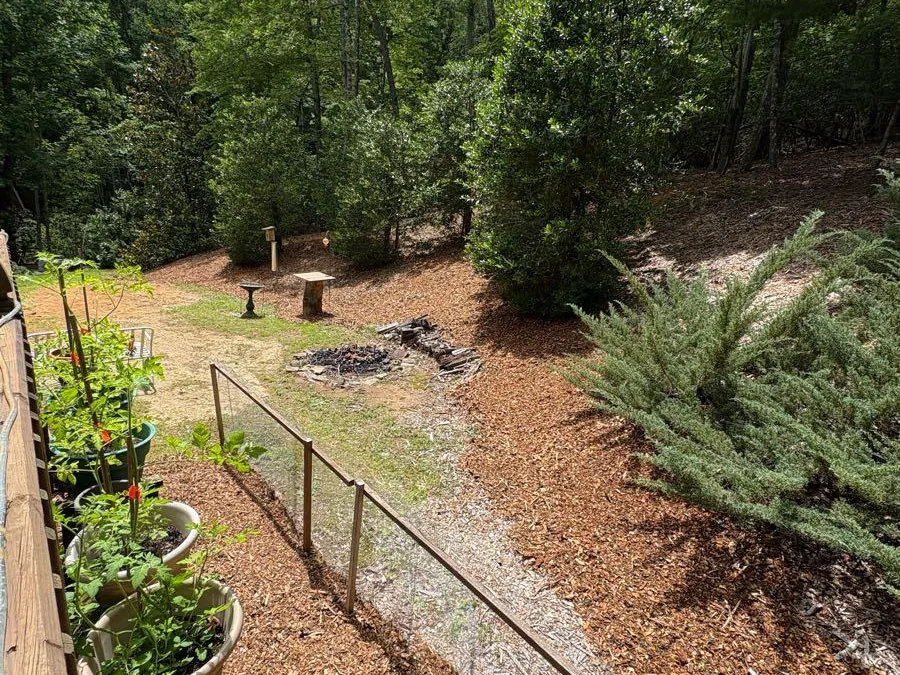 A brown mulch bed along a fence line with potted plants