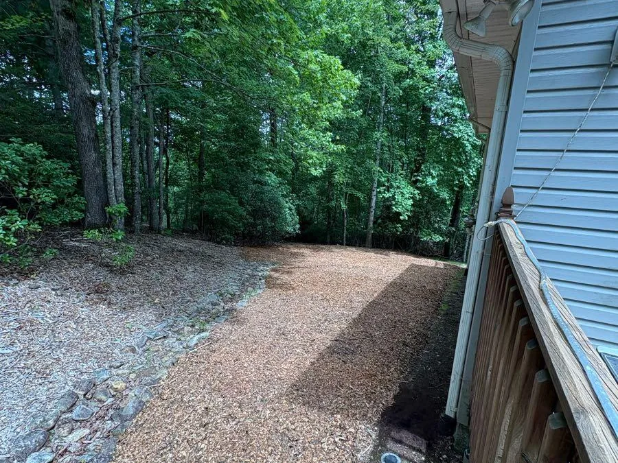 Wood chips installed along the side of a house next to the downspout